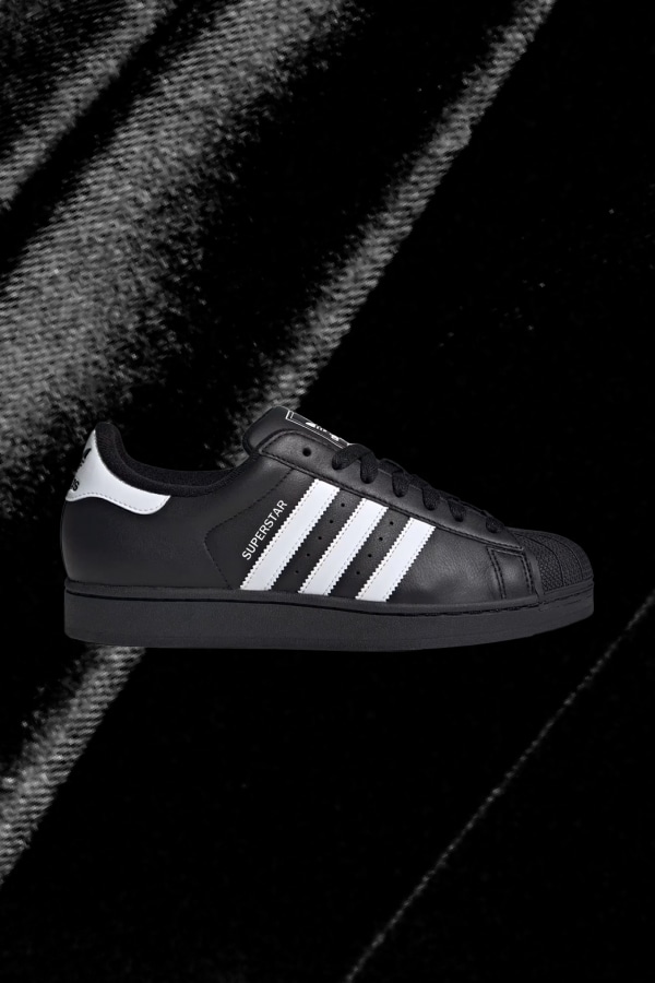 Side view of black Superstar adidas sneaker.