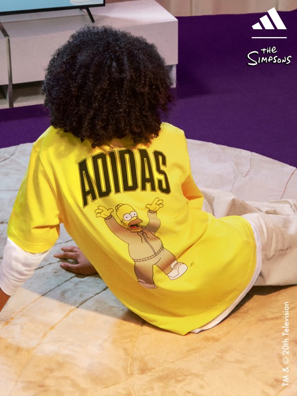 A boy sitting on a rug with his back to the frame wearing Adidas | The Simpsons collection.