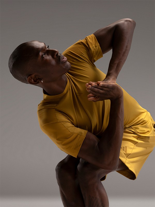 A person in a yellow shirt is captured in a dynamic, expressive pose against a neutral background.