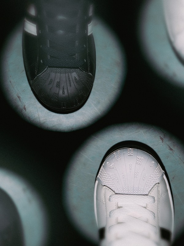 The image shows a close-up view of a pair of white sneakers, with the laces visible, against a dark, blurred background.