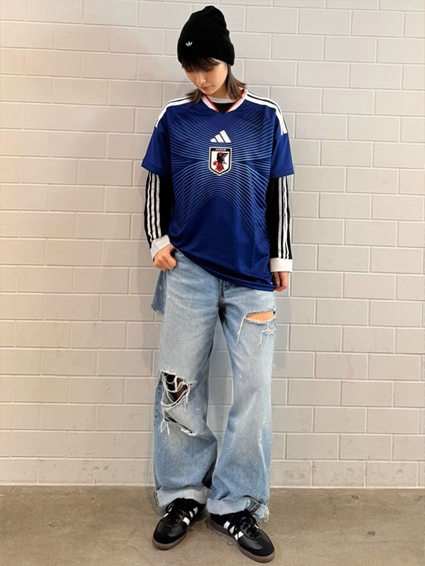 A person wearing a blue and white striped jersey, standing in front of a plain white wall.