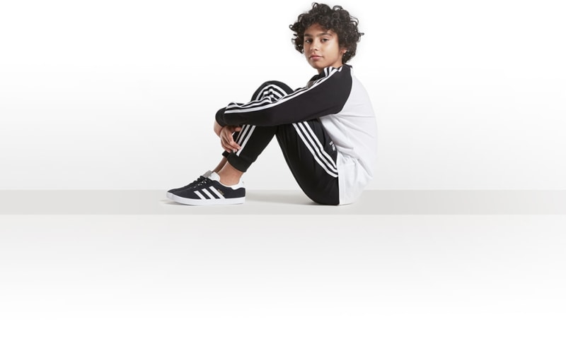 A person wearing a black and white striped outfit sits on the floor against a plain white background.