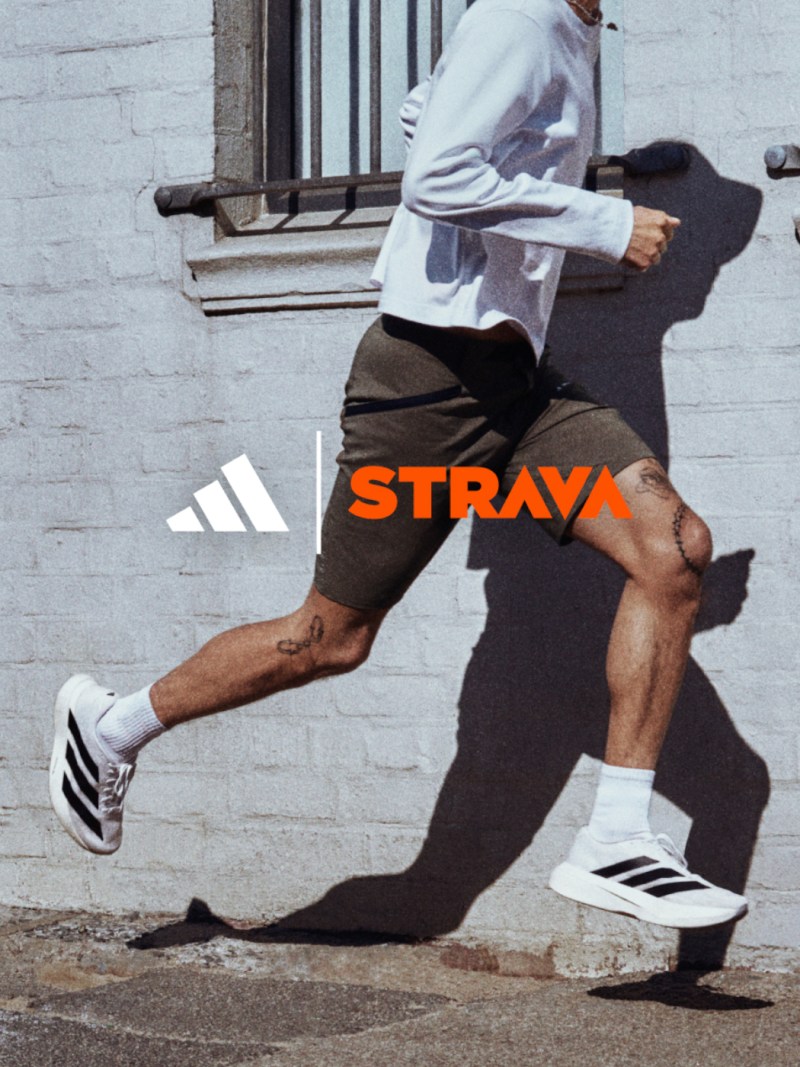 A person wearing athletic clothing and shoes is running or jogging in an urban setting with a building and window visible in the background.