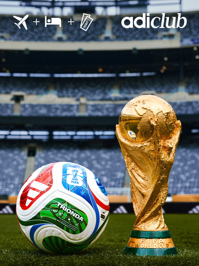 The image shows a soccer ball and the FIFA World Cup trophy on a soccer field, with the Adidas logo visible in the background.