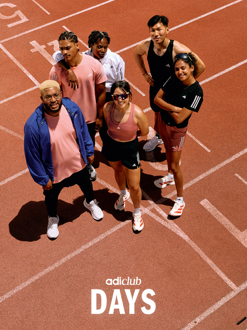 A group of people, dressed in athletic attire, standing on a red running track with the "adidas club DAYS" logo visible in the foreground.