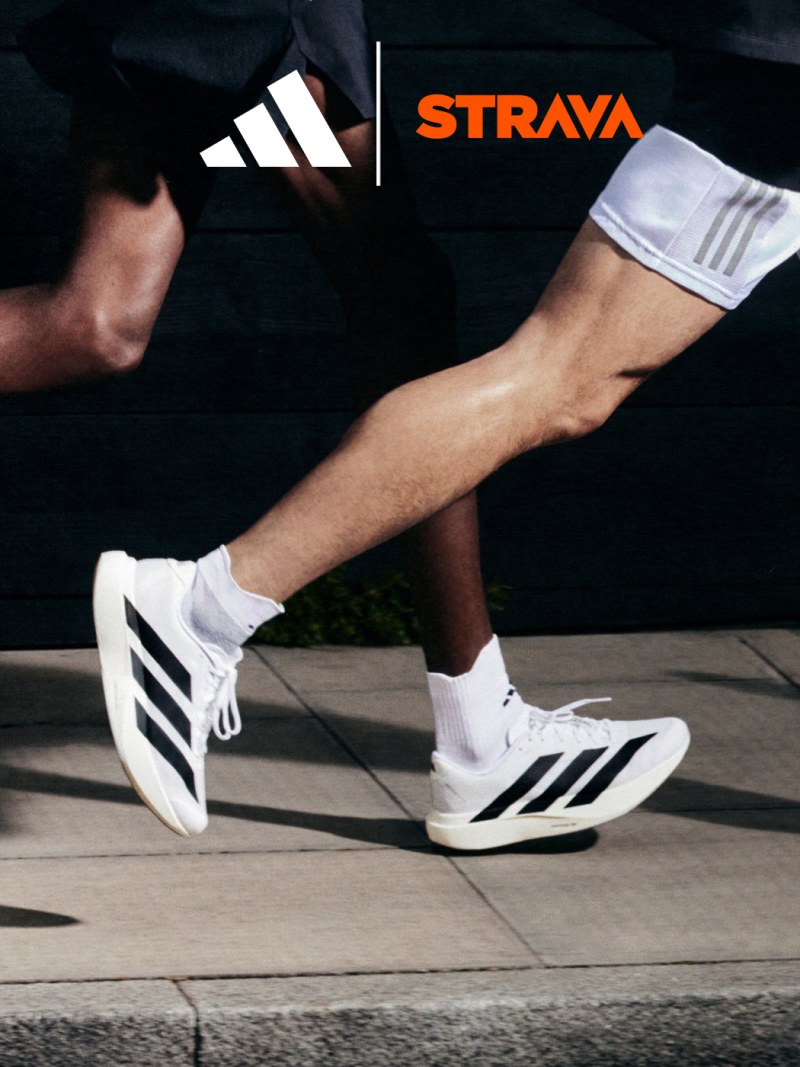 The image shows a person's lower body wearing Adidas athletic shoes and clothing, with the Strava logo prominently displayed on the clothing.
