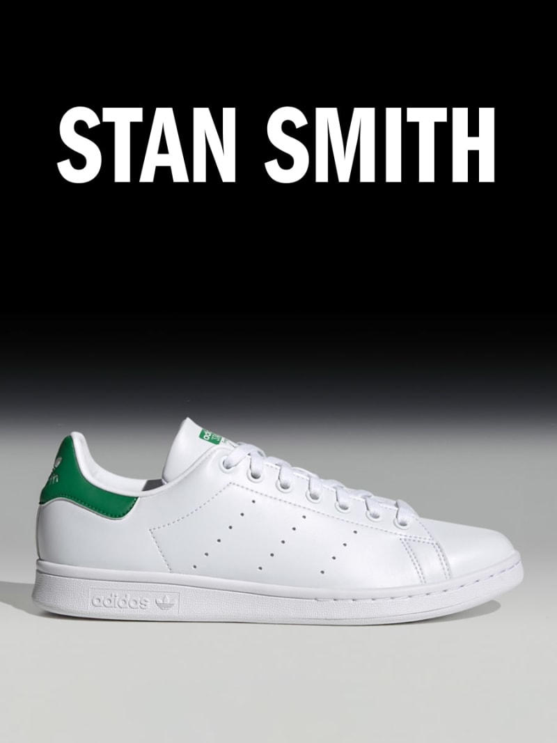 The image shows a pair of white and green Adidas Stan Smith sneakers against a dark background, with the brand name "STAN SMITH" prominently displayed above the shoes.