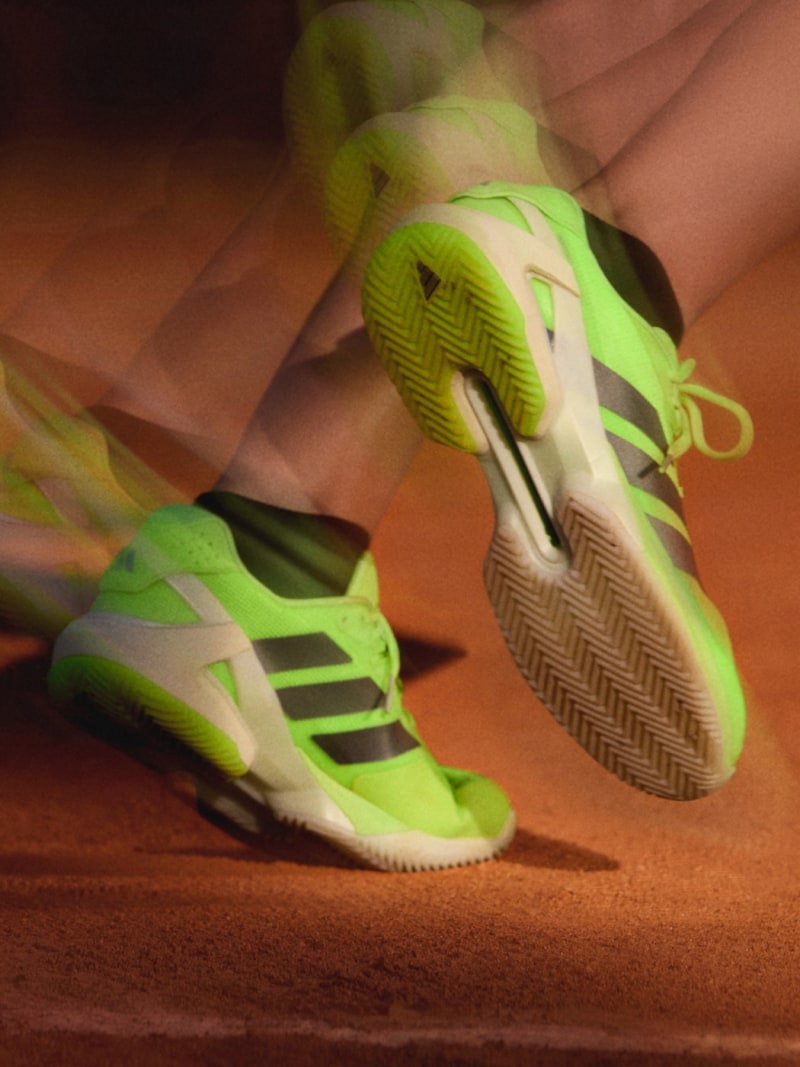 Vibrant green and white athletic shoes with distinctive patterns and treads are prominently displayed on a wooden surface.