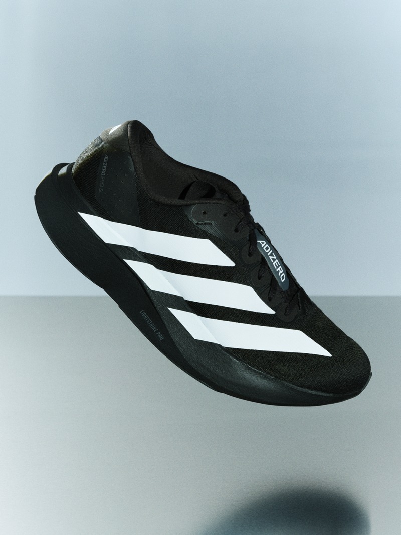 A black and white athletic sandal appears to be floating against a plain, light-colored background.