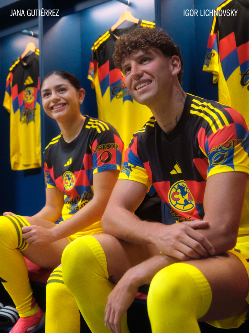 Two individuals wearing yellow and black soccer uniforms with the Club América logo, sitting together and smiling in what appears to be a locker room or team facility.