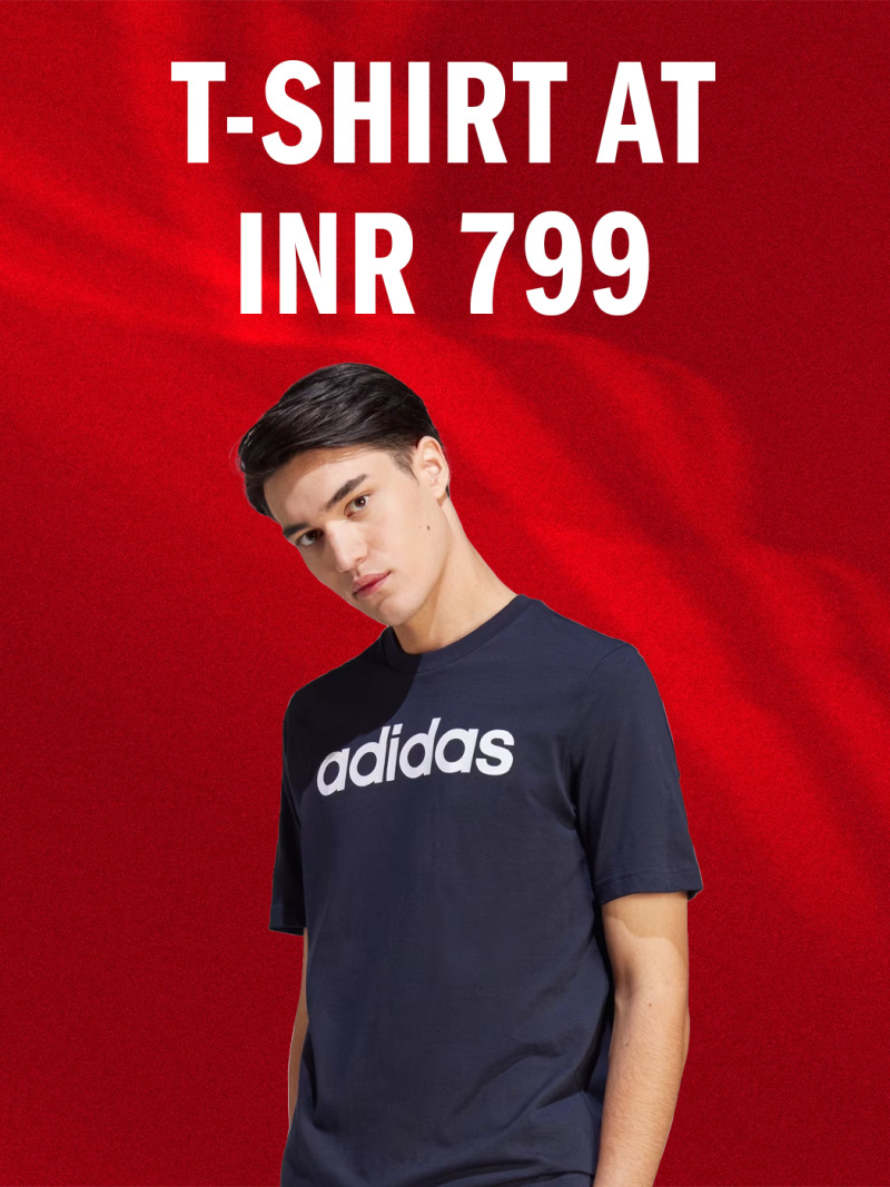 A young man wearing a navy blue Adidas t-shirt stands against a vibrant red background, with text indicating the t-shirt is priced at INR 799.