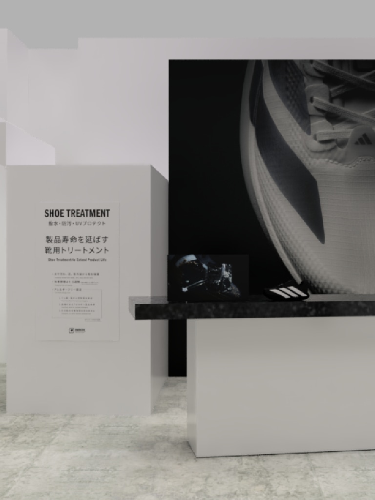 A black and white image showing a shoe treatment sign on a white pedestal, with a large abstract shape in the background.