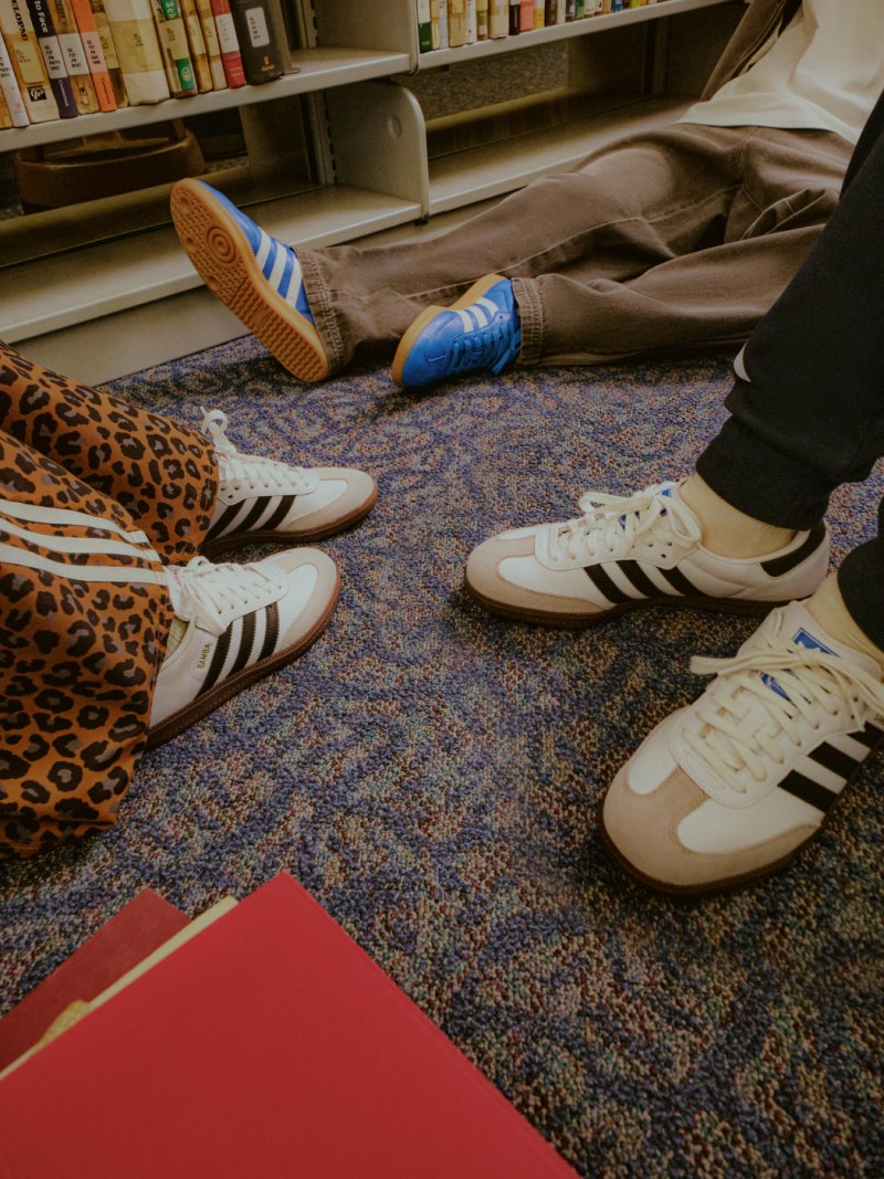 The image shows various pairs of sneakers and shoes, including leopard print and white and blue designs, arranged on a colorful patterned carpet in what appears to be a retail or display setting.