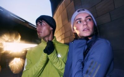 Two individuals, a man and a woman, are standing in an alleyway with a bright light shining in the background, creating an intriguing and dramatic atmosphere.