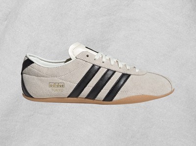 A pair of white and black Adidas sneakers with a gum sole, set against a plain light-colored background.