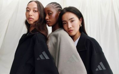 The image features three young women with serious expressions, dressed in dark-colored clothing against a plain background.