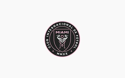 The image shows the logo of the Inter Miami CF soccer club, featuring a stylized "M" and the text "INTERNACIONAL DE FUTBOL MIAMI" in a black and pink color scheme.