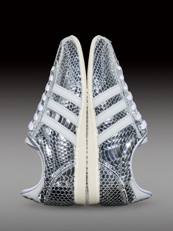 A pair of white and gray sneakers with a snakeskin-like pattern, set against a dark background.