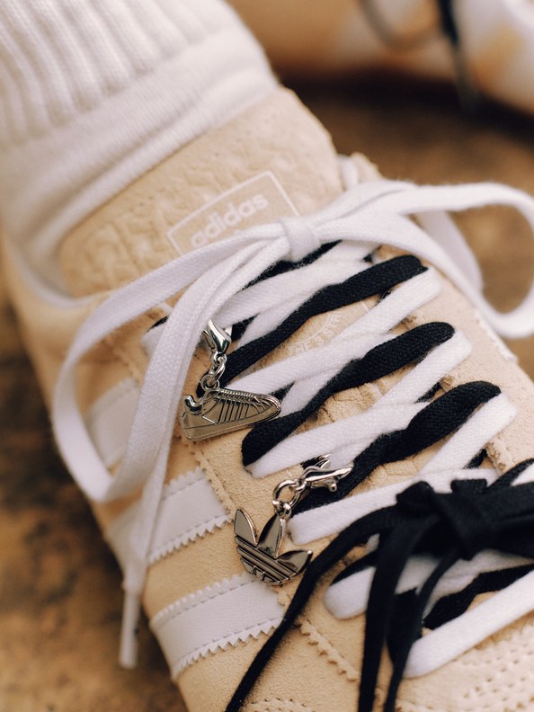 A pair of white and tan sneakers with black and white striped laces, resting on a wooden surface.