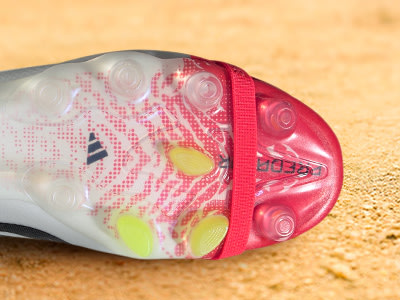 A close-up view of a vibrant, patterned athletic shoe with a red lace against a sandy background.