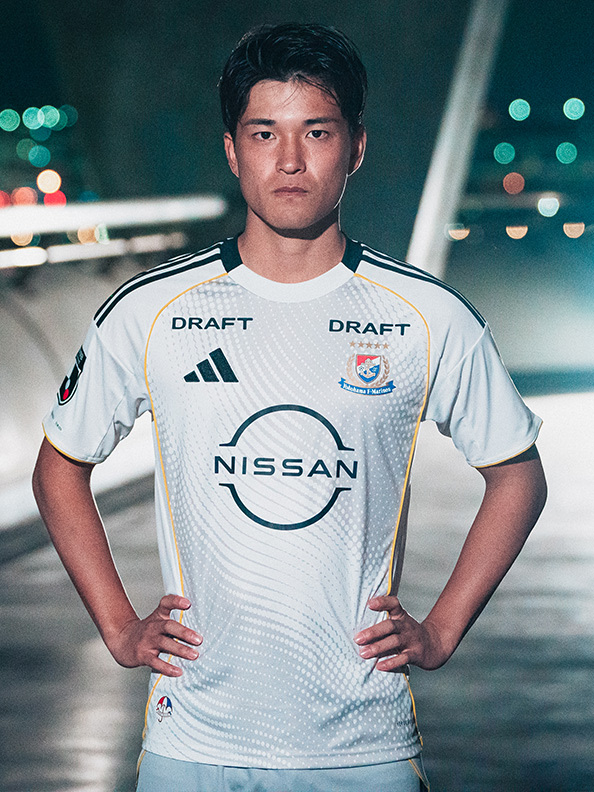 The image shows a young man wearing a white sports jersey with the Nissan logo and "Draft" written on it, standing in front of a nighttime cityscape with blurred lights in the background.