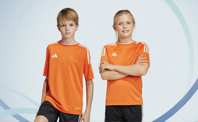 Two young individuals wearing orange sports jerseys with white stripes stand in front of a light blue background.