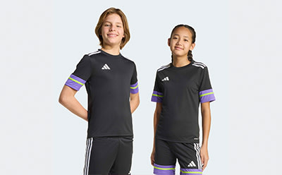 Two young individuals wearing black athletic jerseys with purple and white stripes stand against a plain white background.
