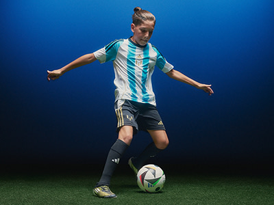 A soccer player in a striped jersey is dribbling a ball on a green field against a deep blue background.