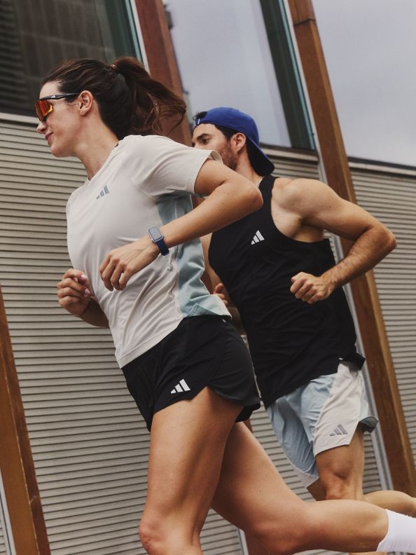 Two people, a woman and a man, are engaged in a physical activity or exercise outdoors, with a building or structure visible in the background.