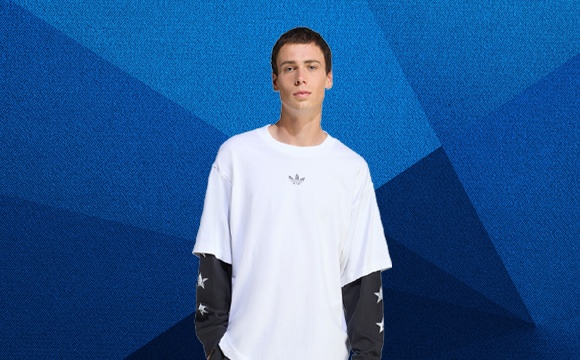 A person wearing a white t-shirt stands against a vibrant blue background with geometric shapes.