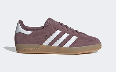 A pair of burgundy Adidas sneakers with white stripes and a gum sole, set against a plain white background.