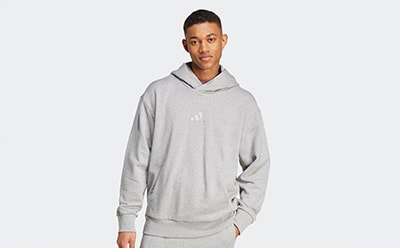 The image shows a young man wearing a gray hooded sweatshirt against a plain white background.