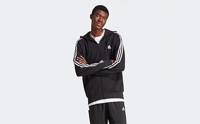 A young person wearing a black hooded jacket and pants, standing against a plain white background.