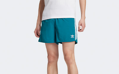 The image shows a pair of teal-colored athletic shorts with the Adidas logo prominently displayed.