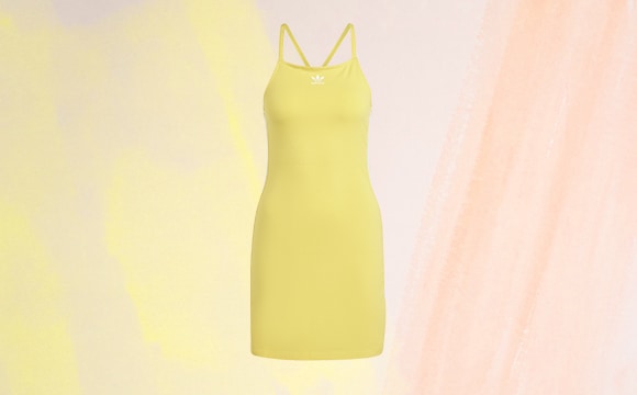 A vibrant yellow dress hangs against a soft, pastel-colored background, creating a visually striking and minimalist composition.