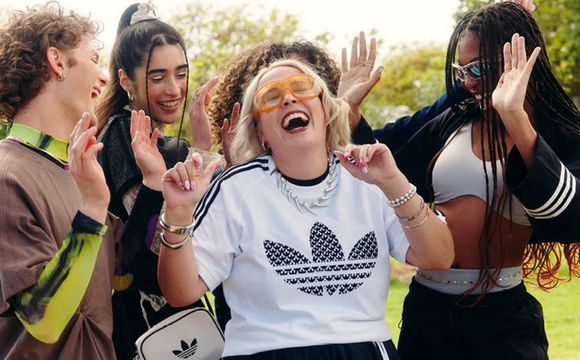 A group of young, diverse individuals are gathered outdoors, laughing and celebrating together in a joyful and energetic manner.