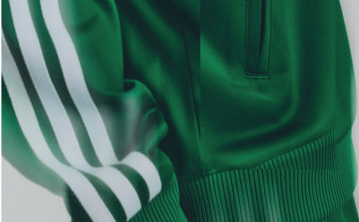 Detail of a green Adidas track jacket with white sleeve stripes.