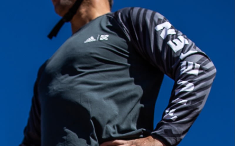 En person, der har en sort og grå atletisk jakke på, står på en strålende blå baggrund.