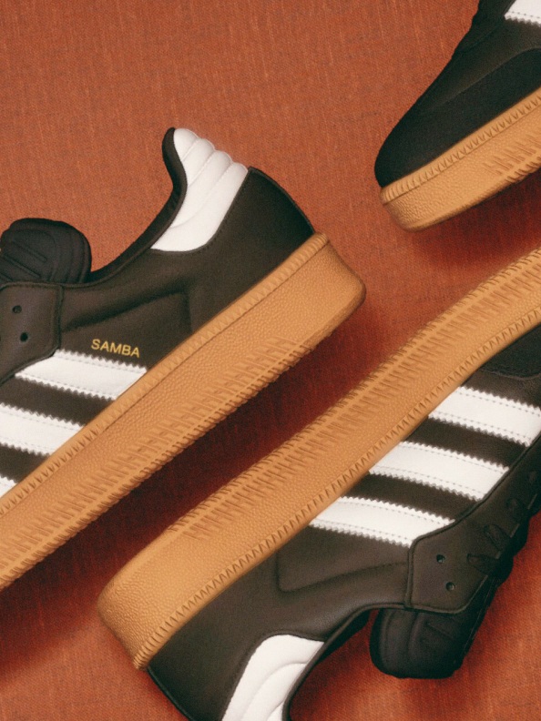 A pair of black and white sneakers with a gum sole sits on a striped background, creating a visually appealing contrast.