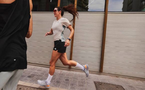 A person in athletic clothing is running on a tiled surface, with a glass wall and outdoor scenery visible in the background.