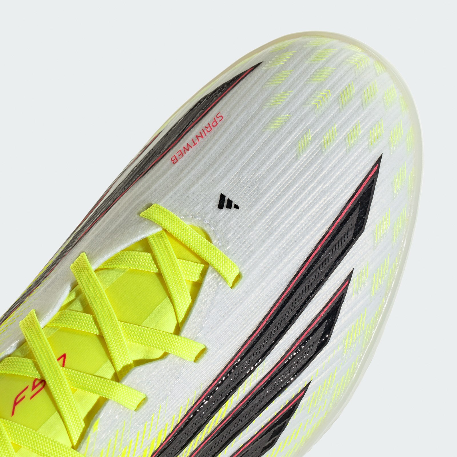 A close-up view of a white and yellow athletic shoe with laces and a textured sole, set against a plain white background.