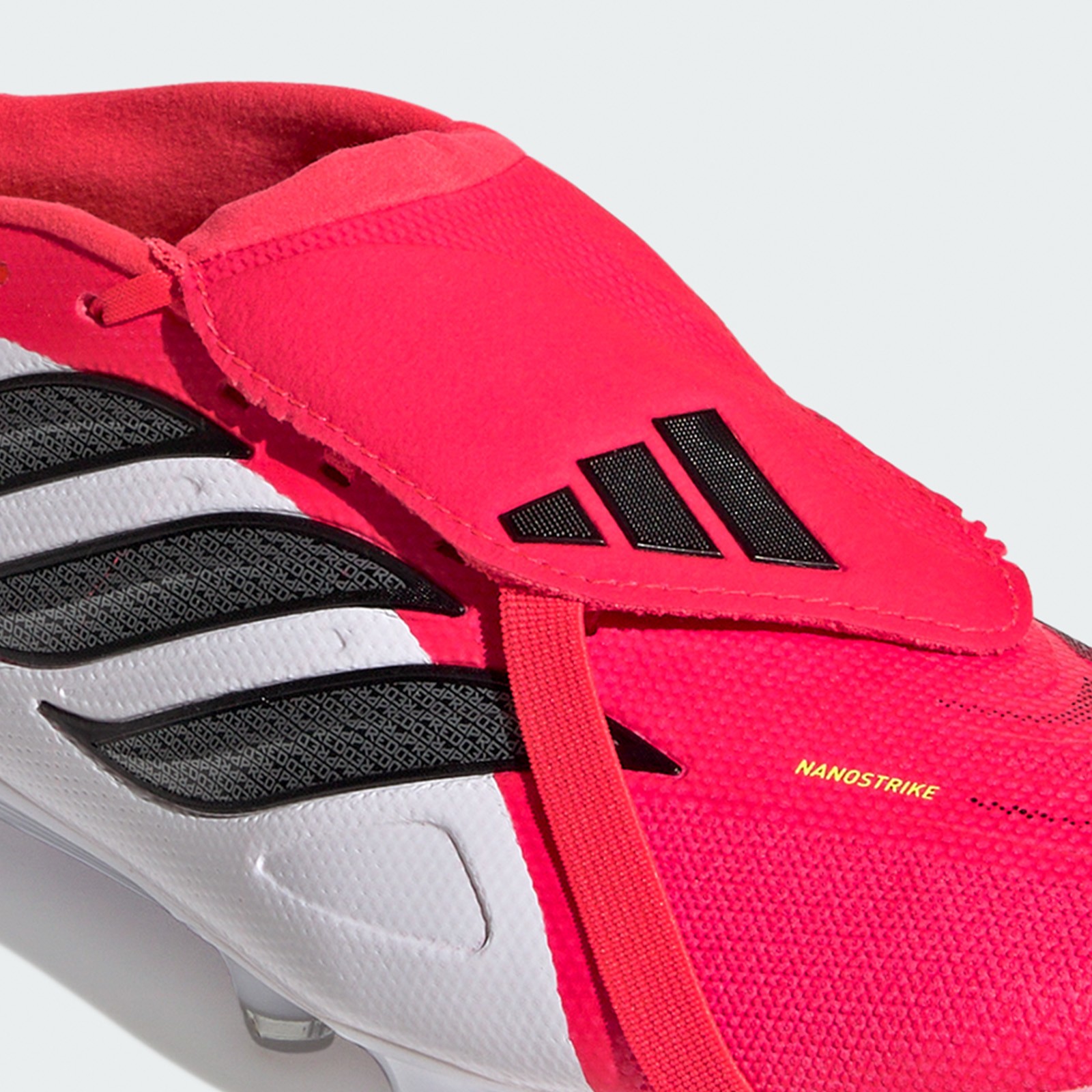 A close-up view of a bright red and black athletic shoe with the Adidas logo prominently displayed.