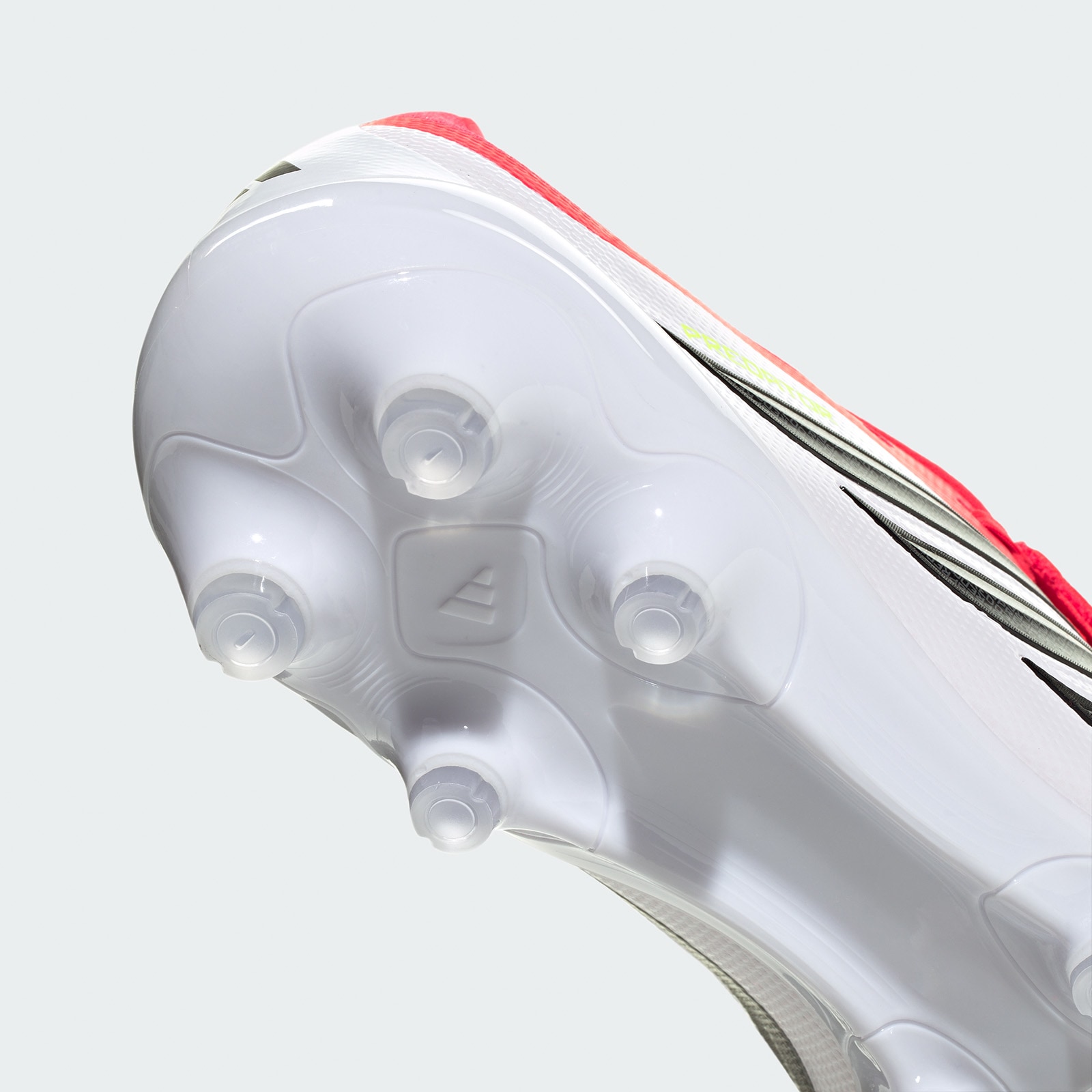 A close-up view of a white and red soccer cleat with a textured surface and multiple studs on the sole.