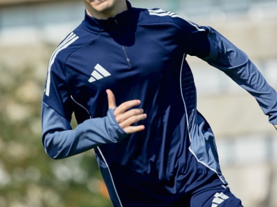 En röd adidasjacka med vita ränder mot vit bakgrund.
