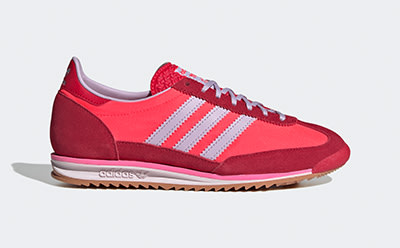 A vibrant red and pink sneaker with white stripes and a gum sole, set against a plain background.