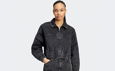 The image shows a person wearing a black denim jacket with a collar, standing against a plain white background.