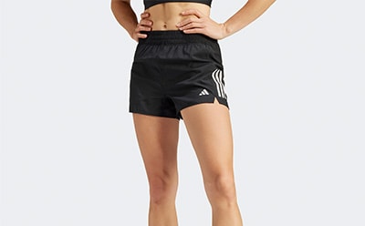 The image shows a person wearing black athletic shorts with white stripes on the sides, standing against a plain white background.