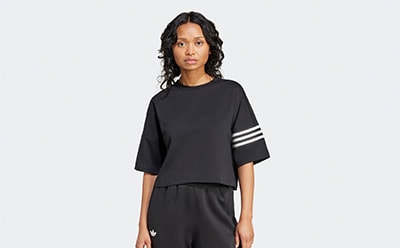 The image shows a person wearing a black top with white stripes on the sleeves, standing against a plain white background.