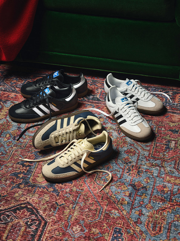 A collection of various athletic shoes, including sneakers and running shoes, rests on a colorful patterned rug in the foreground.