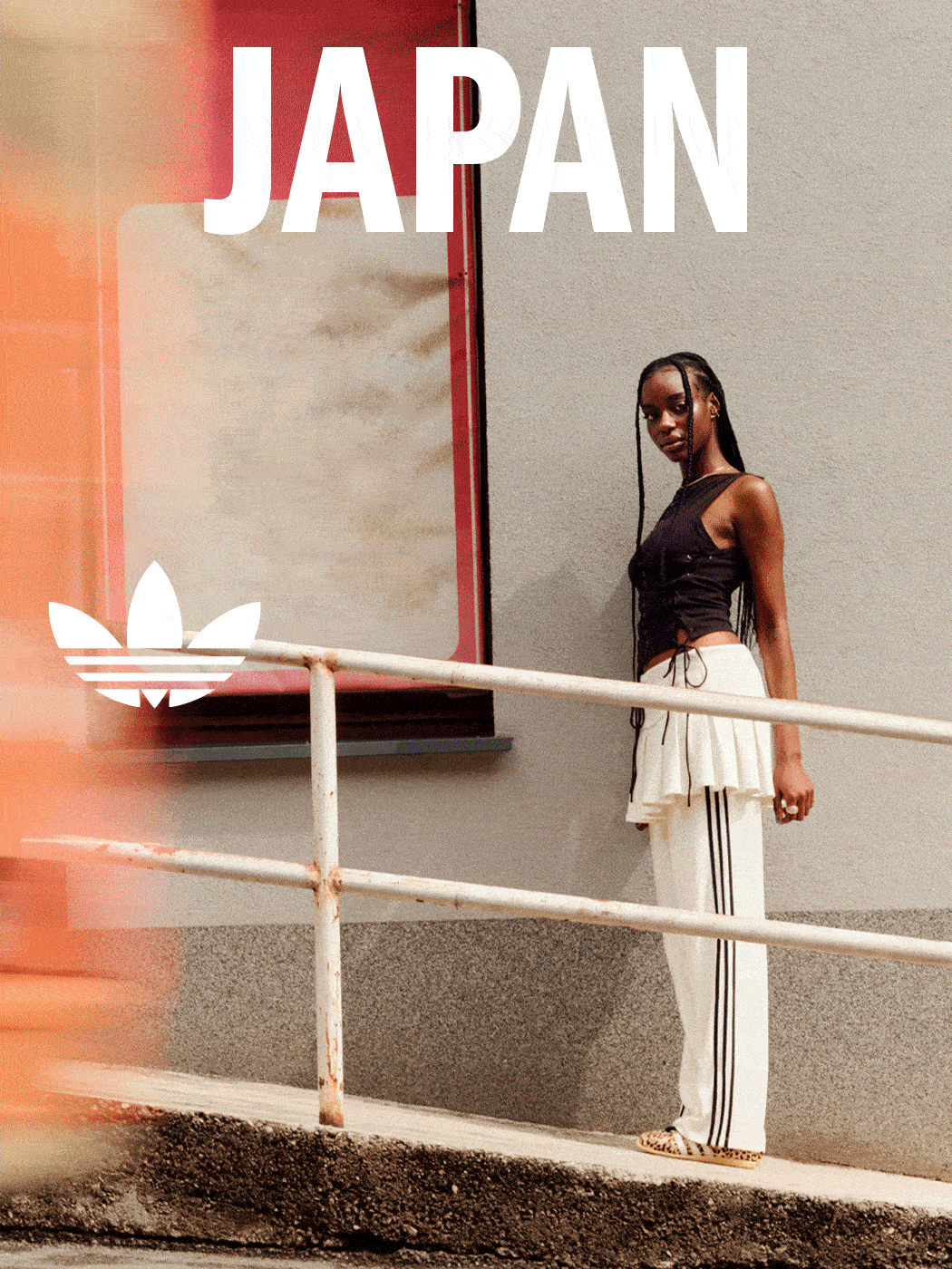 A woman stands in front of a large "JAPAN" sign, wearing a black top and white striped pants, with a red and orange background.